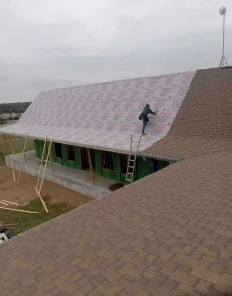 Worker preparing underlayment for a metal roof installation in Estherville